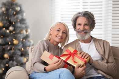 Happy couple opening Christmas gift at home