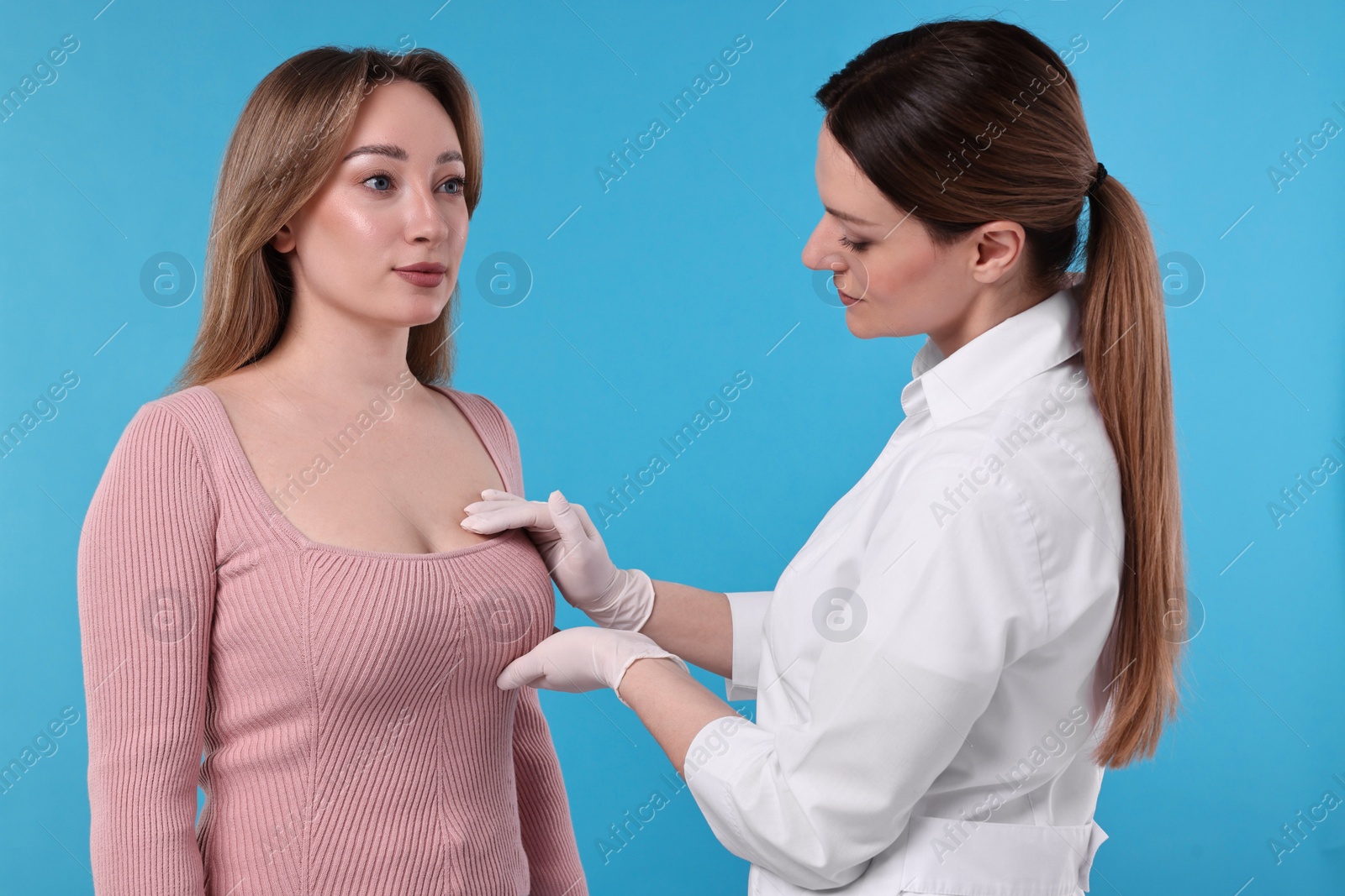 Photo of Mammologist checking woman's breast on light blue background