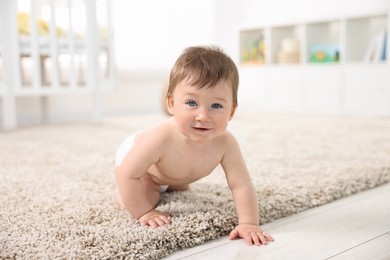 Cute baby boy crawling on carpet at home