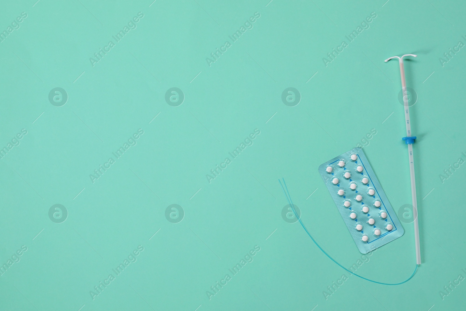 Photo of Contraception choice. Pills and intrauterine device on turquoise background, flat lay. Space for text