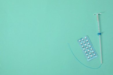 Contraception choice. Pills and intrauterine device on turquoise background, flat lay. Space for text