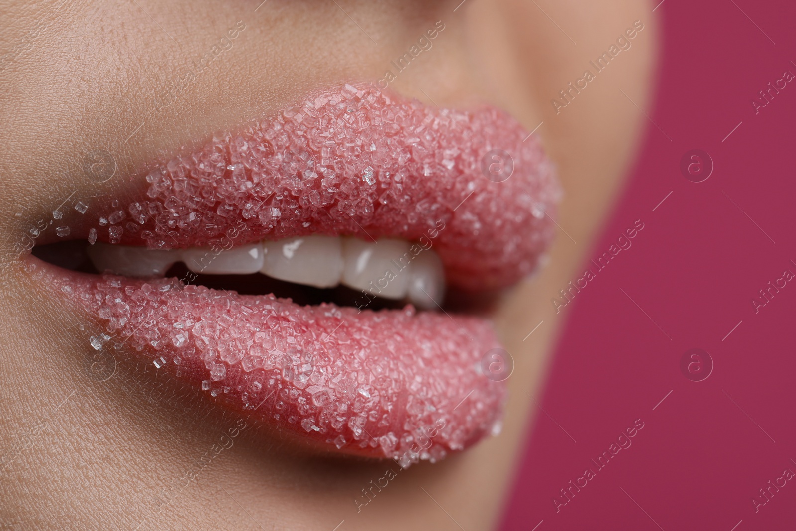 Photo of Young woman with beautiful lips covered in sugar, on pink background, closeup