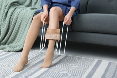 Photo of Woman wearing compression tights with donner on sofa indoors, closeup. Space for text