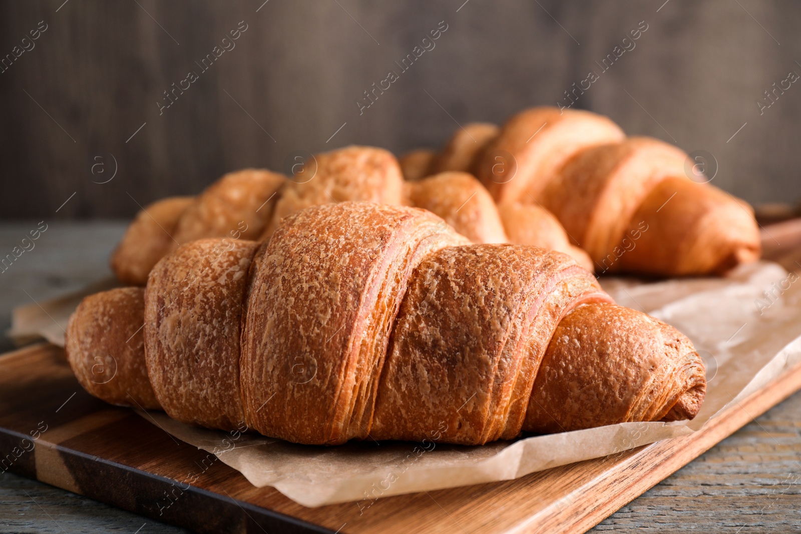 Photo of Tasty fresh croissants on wooden table, closeup