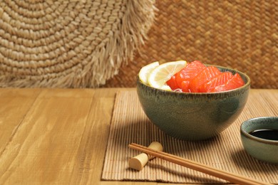 Delicious salmon sashimi served with funchosa, lemon and soy sauce on wooden table. Space for text