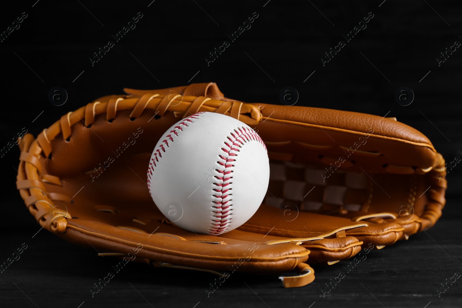 Photo of Catcher's mitt and baseball ball on black background. Sports game