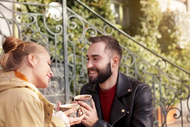 Lovely young couple enjoying tasty coffee on sunny day outdoors