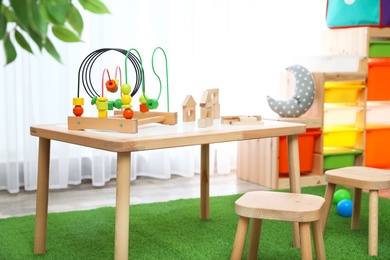 Photo of Stylish playroom interior with toys and modern wooden furniture