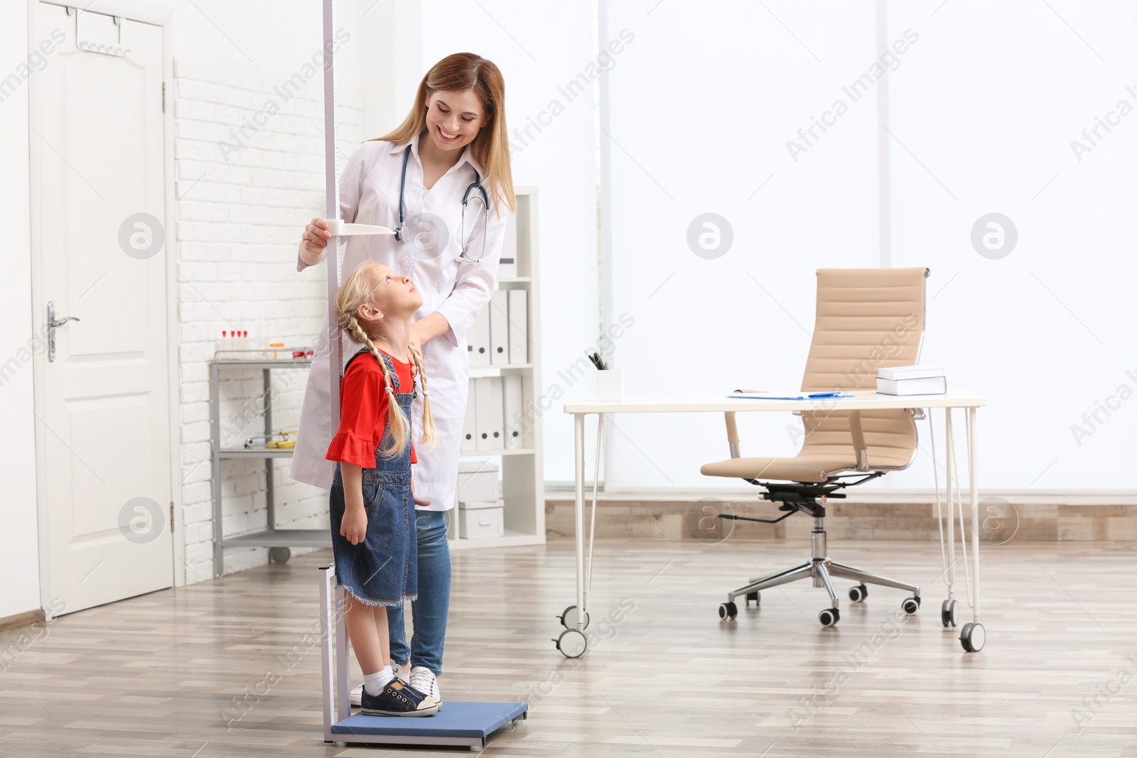 Photo of Doctor measuring little girl's height in hospital