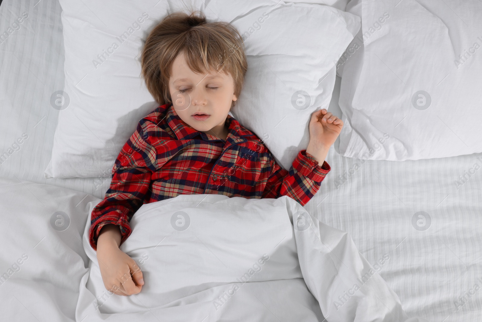 Photo of Little boy snoring while sleeping in bed, top view