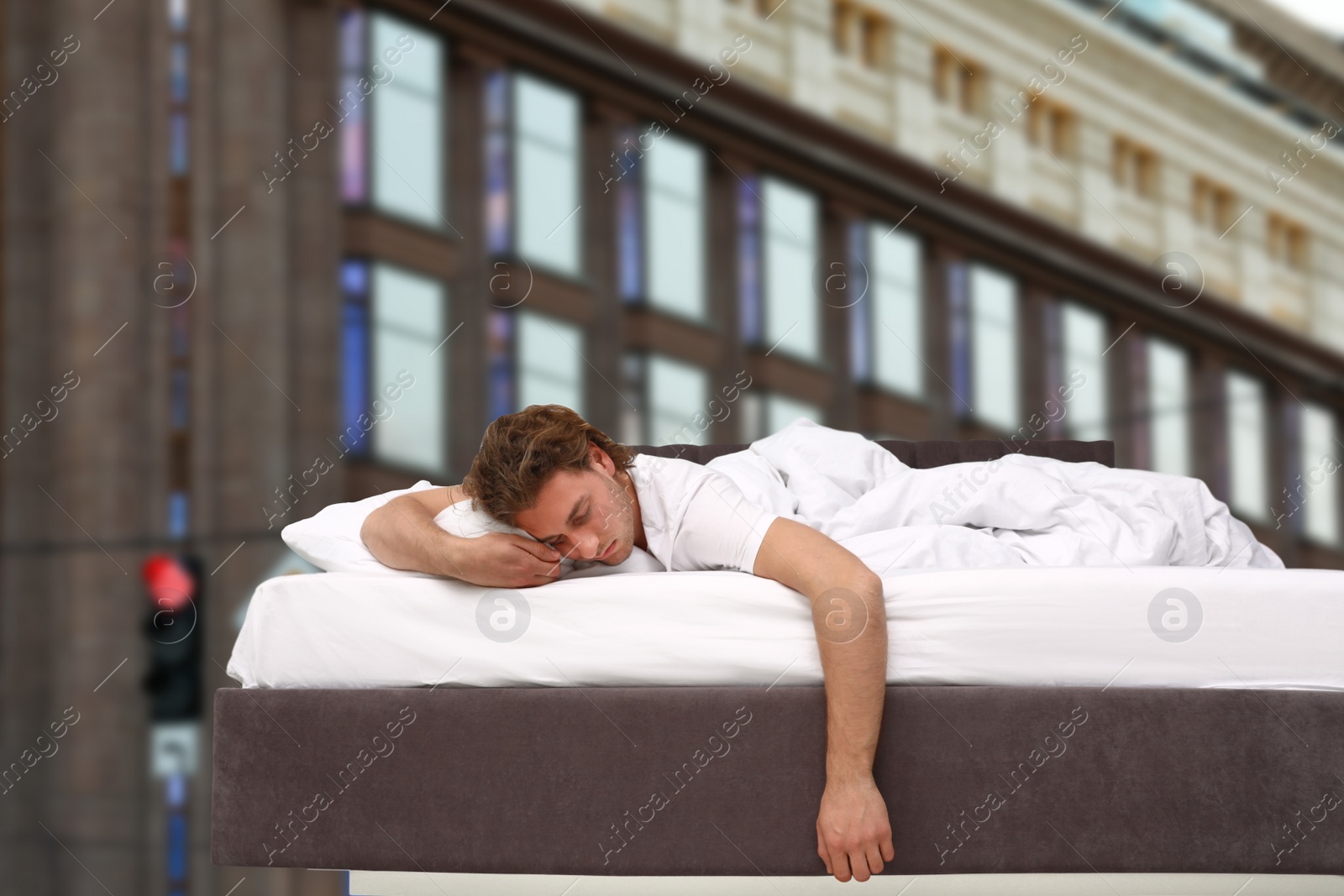 Image of Man sleeping in bed and beautiful view of building on background. Good sleep despite of urban noise