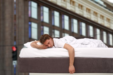 Image of Man sleeping in bed and beautiful view of building on background. Good sleep despite of urban noise