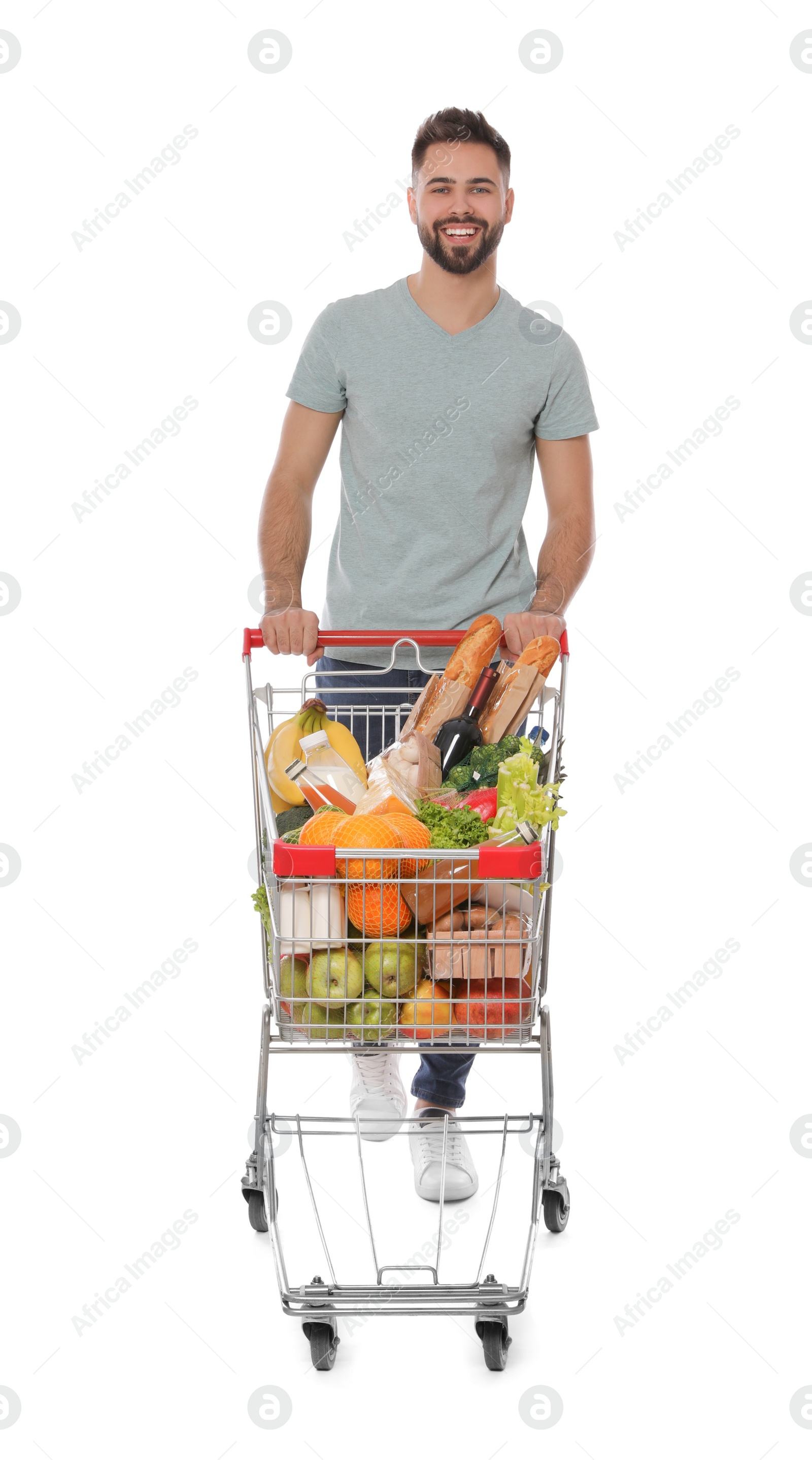 Photo of Happy man with shopping cart full of groceries on white background