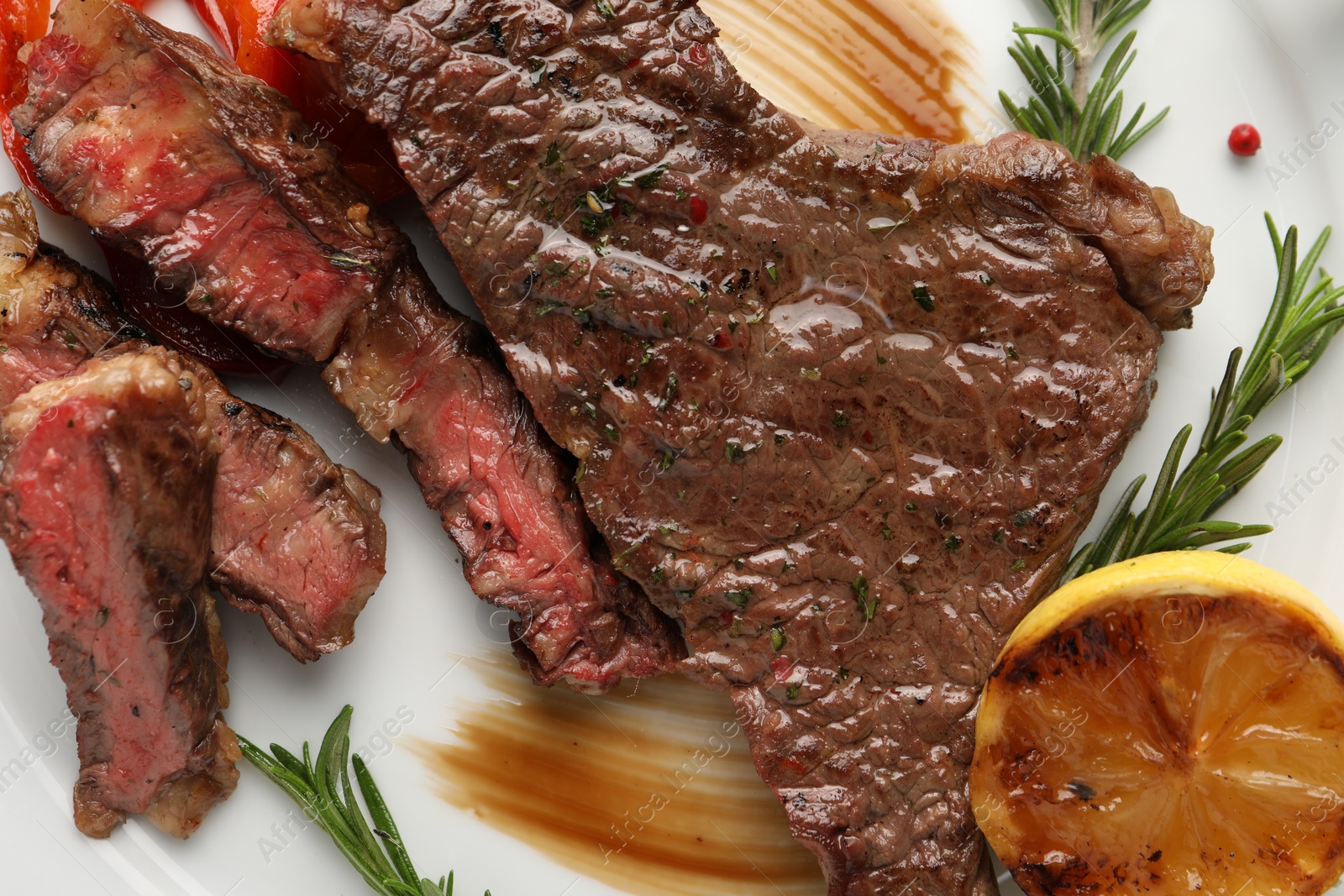 Photo of Delicious grilled beef steak with spices and lemon served on plate, top view