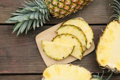 Photo of Cut and whole ripe pineapples on wooden table, flat lay