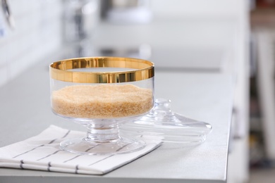 Photo of Jar of raw rice on light grey table in modern kitchen