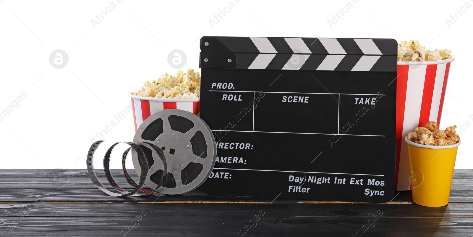 Photo of Movie clapper, buckets of tasty popcorn and film reel on wooden table against white background