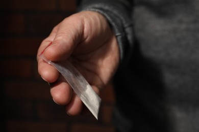 Drug addiction. Man with plastic bag of cocaine on blurred background, closeup