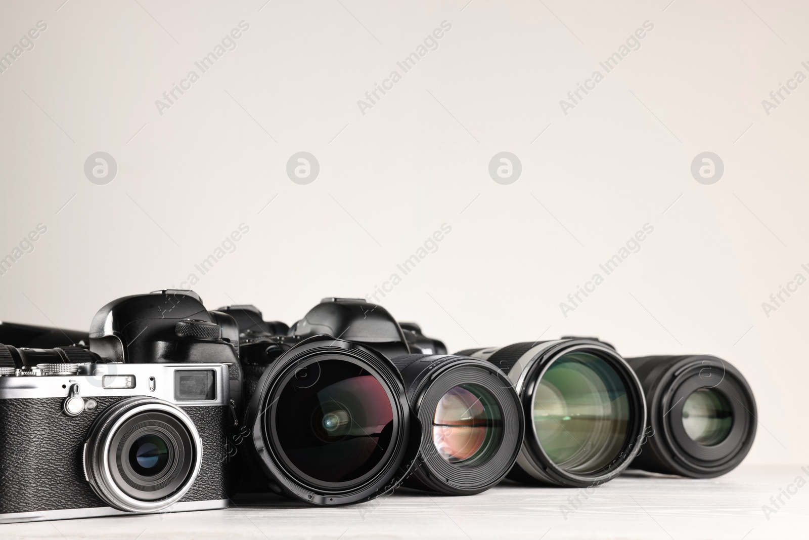 Photo of Modern cameras on white wooden table, space for text