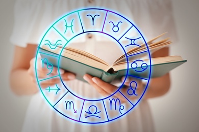 Image of Young woman reading book and illustration of zodiac wheel with astrological signs on light background 