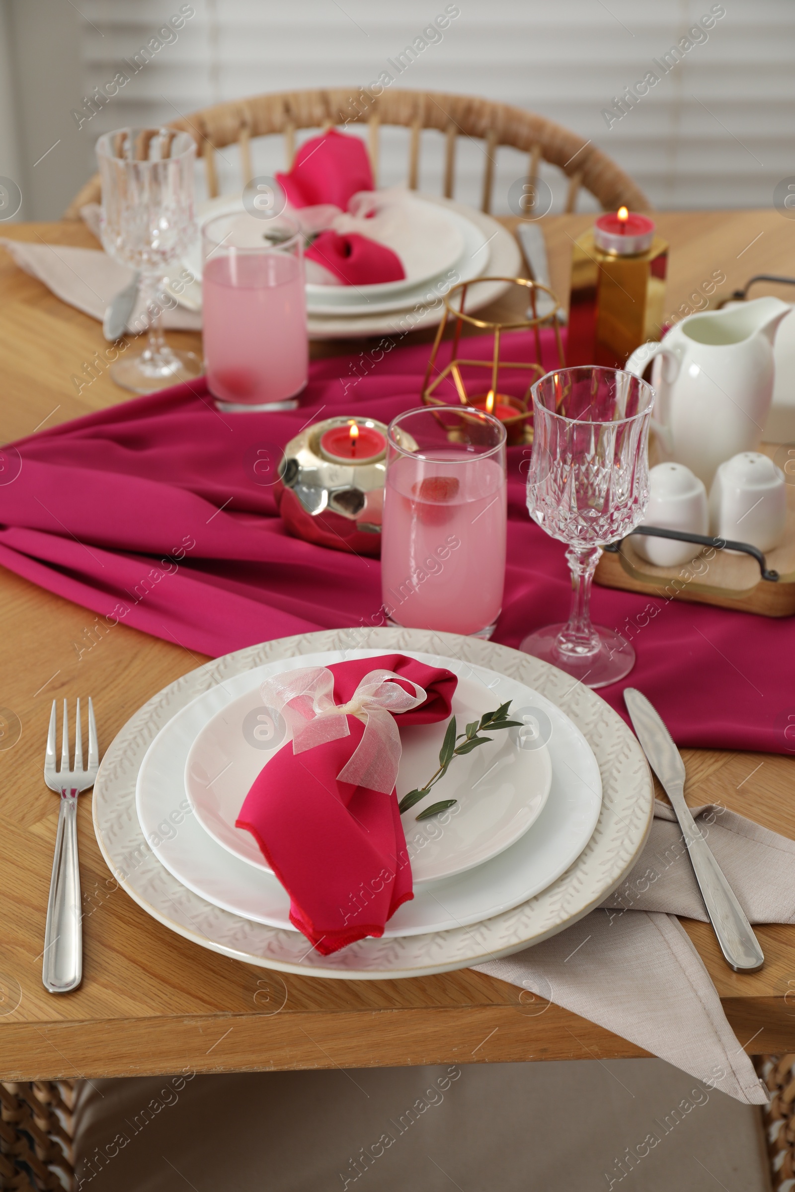 Photo of Color accent table setting. Plates with pink napkins, glasses and cutlery, closeup