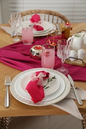 Photo of Color accent table setting. Plates with pink napkins, glasses and cutlery, closeup