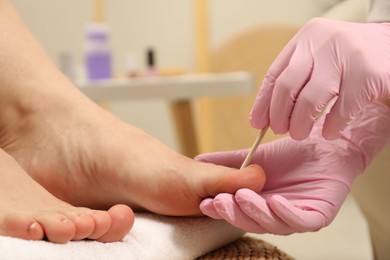 Photo of Professional pedicurist working with client`s toenails in beauty salon, closeup