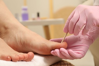 Professional pedicurist working with client`s toenails in beauty salon, closeup