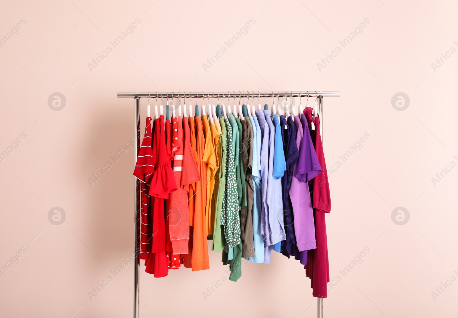 Photo of Wardrobe rack with different bright clothes on color background