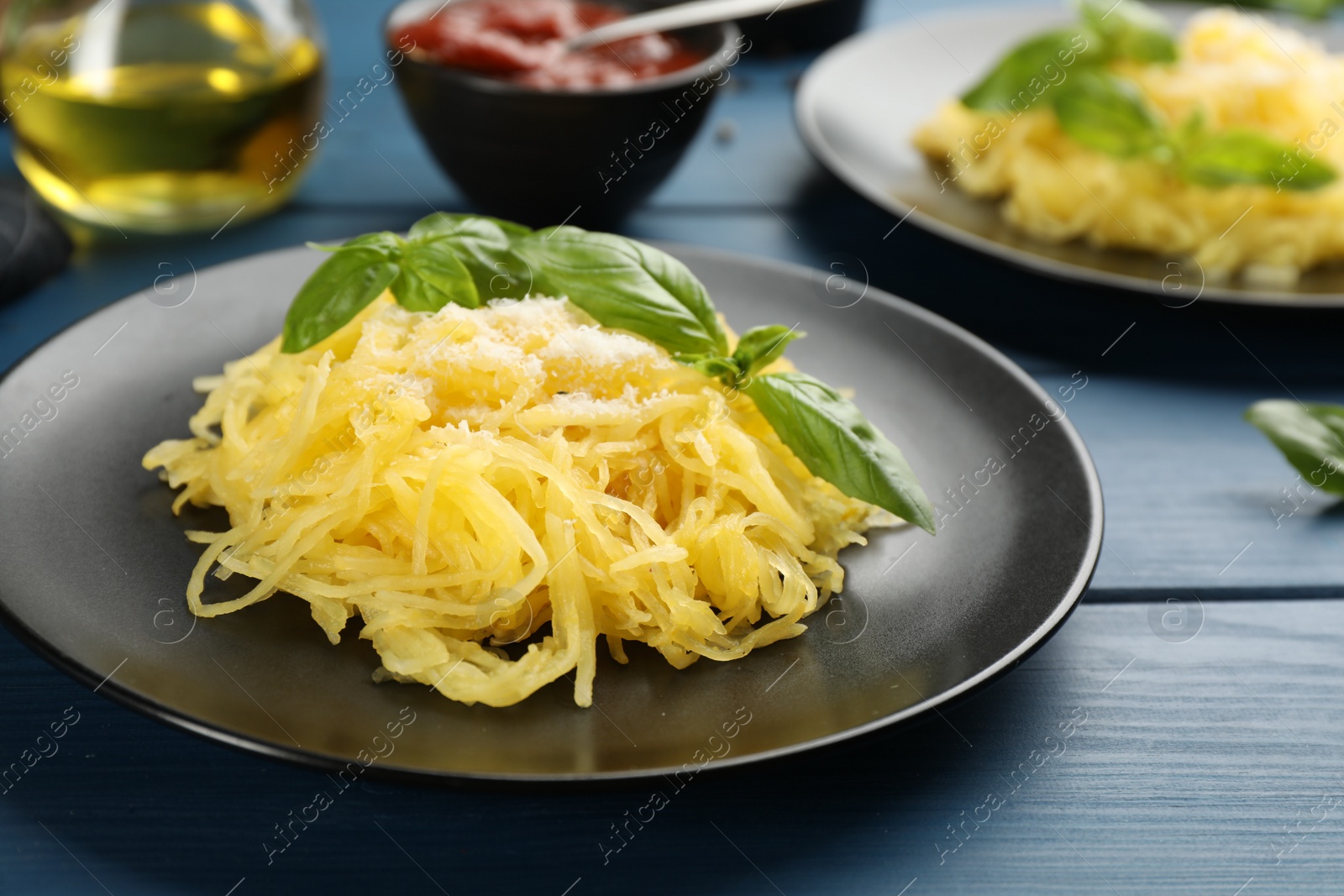 Photo of Tasty spaghetti squash with basil and cheese served on blue wooden table, closeup