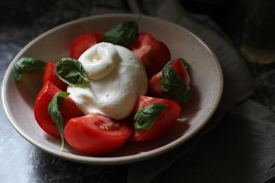 Photo of Delicious burrata cheese with tomatoes and basil on grey table, closeup. Space for text