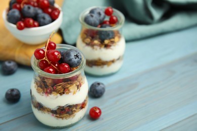 Photo of Delicious yogurt parfait with fresh berries on turquoise wooden table, closeup. Space for text