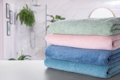 Image of Stack of fresh towels on light grey table in bathroom