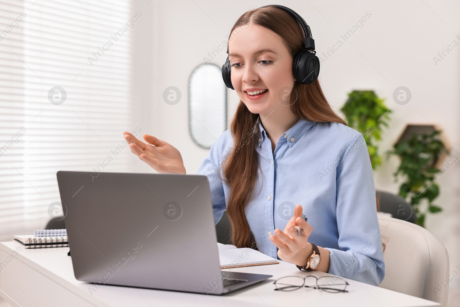 Photo of E-learning. Young woman using laptop during online lesson at white table indoors