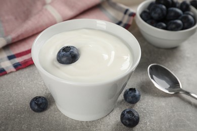 Photo of Bowl with delicious yogurt and blueberries on grey table, closeup