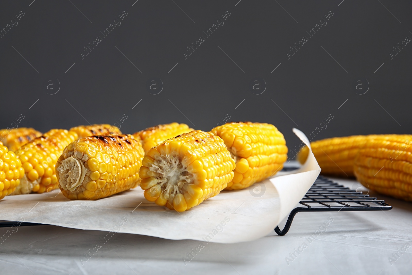 Photo of Cooling rack with grilled corn cobs on light table