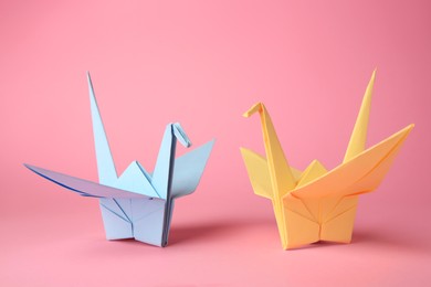 Photo of Origami art. Colorful handmade paper cranes on pink background
