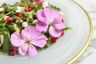Photo of Fresh spring salad with flowers on white marble table, closeup