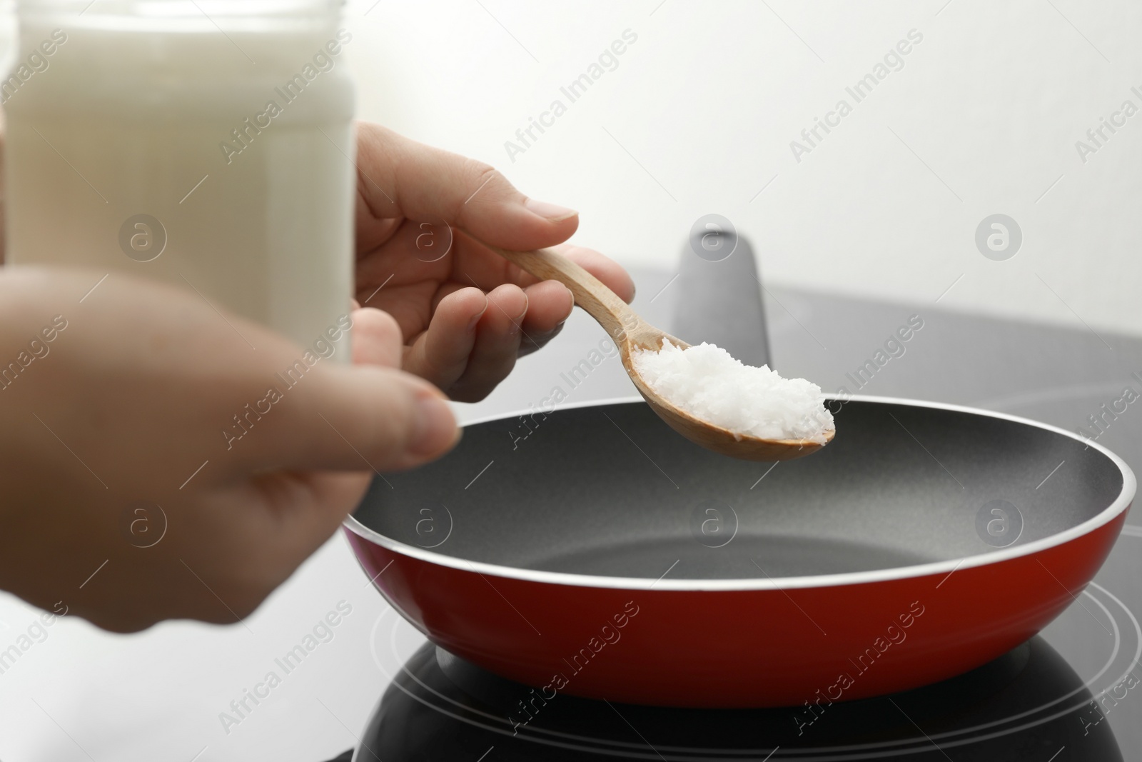 Photo of Woman cooking with coconut oil on induction stove, closeup