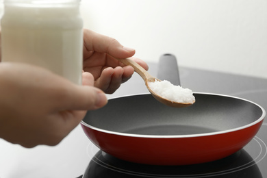 Photo of Woman cooking with coconut oil on induction stove, closeup