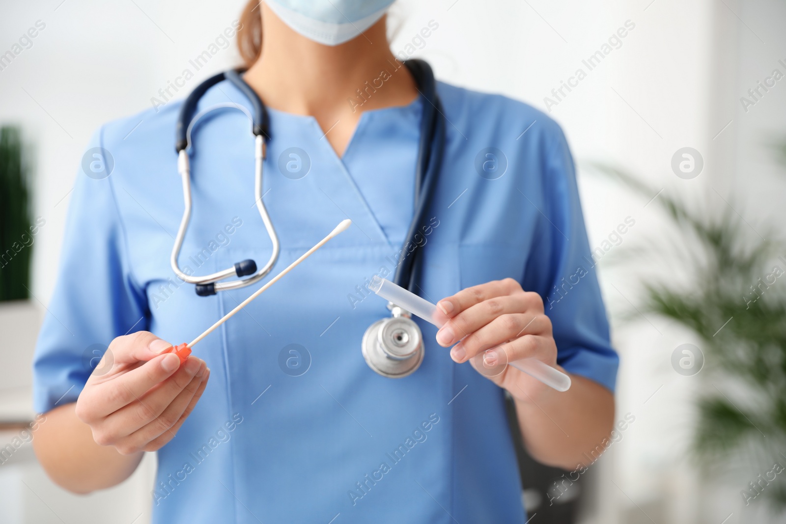 Photo of Doctor holding buccal cotton swab and tube for DNA test in clinic, closeup