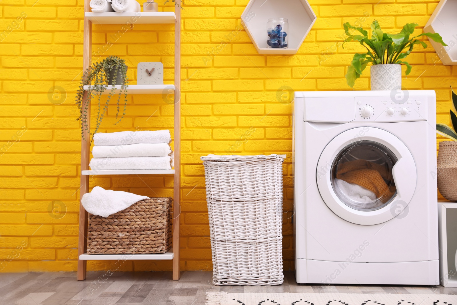 Photo of Laundry room interior with modern washing machine near yellow brick wall