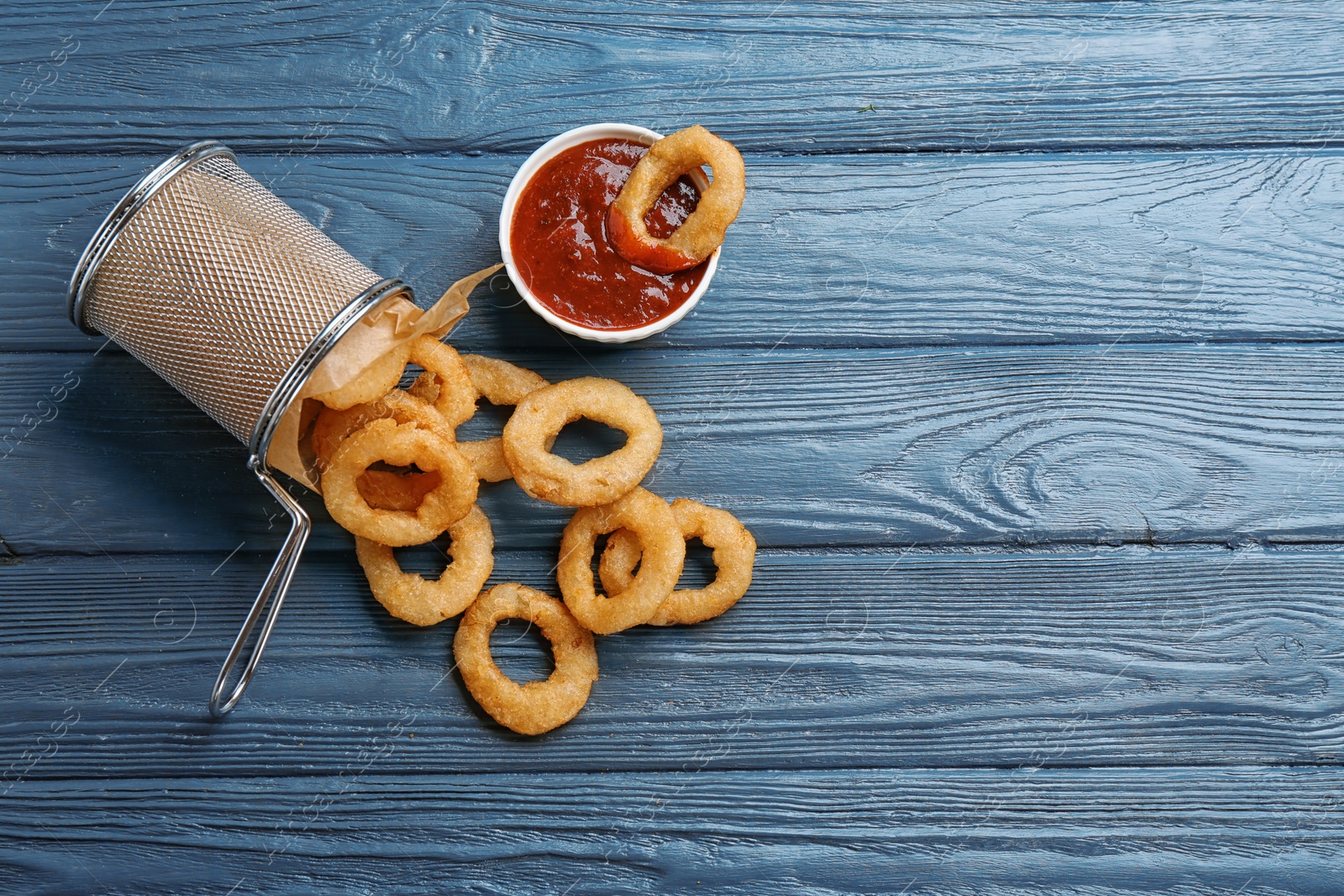 Photo of Flat lay composition with fried onion rings and sauce on wooden background