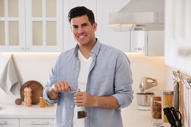 Photo of Man using manual coffee grinder in kitchen
