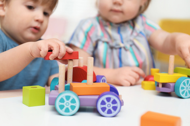 Photo of Little children playing with construction set at table, closeup