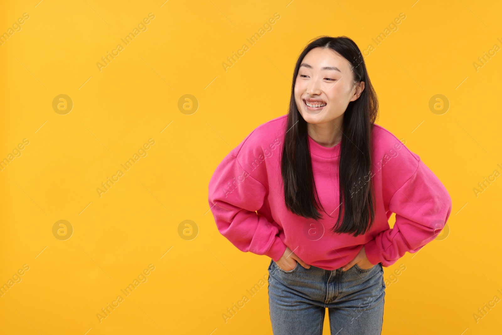 Photo of Portrait of smiling woman on orange background. Space for text