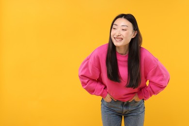 Portrait of smiling woman on orange background. Space for text