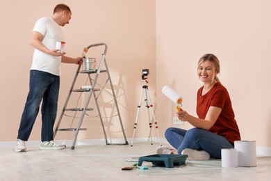 Photo of Happy couple with painting tools in apartment during repair