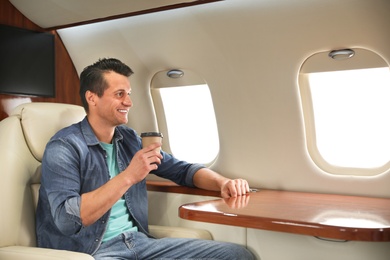 Image of Handsome man with paper cup on plane. Air travel