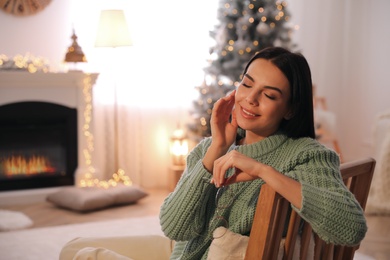 Young woman in armchair at home, space for text. Christmas celebration